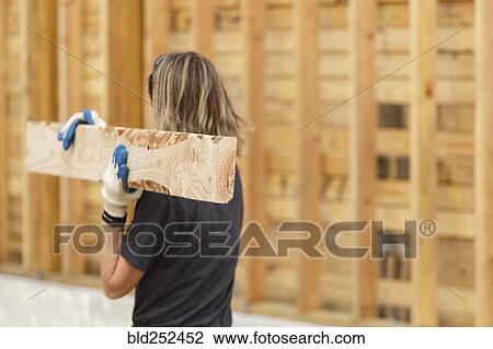 Caucasian woman carrying lumber at construction site View Large Photo Image Stock Image - Caucasian woman carrying lumber at construction site. Fotosearch