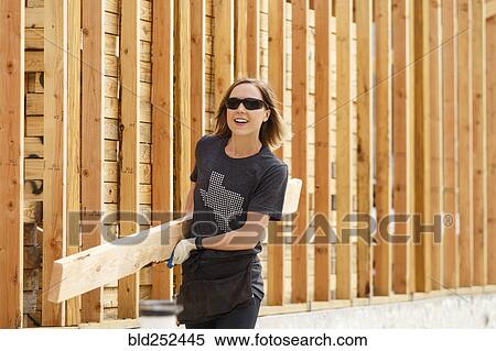 Caucasian woman carrying lumber at construction site View Large Photo Image Stock Photography - Caucasian woman carrying lumber at construction site. Fotosearch