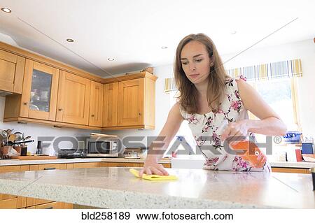 Stock Photo - Caucasian woman cleaning kitchen counter. Fotosearch
