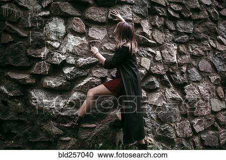 Stock Image - Caucasian woman climbing rock wall. Fotosearch