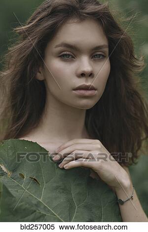 Stock Photography - Caucasian woman covering chest with leaf. Fotosearch
