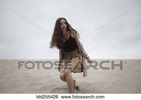 Stock Photograph - Caucasian woman crouching at beach. Fotosearch