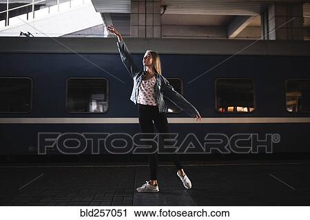Stock Image - Caucasian woman dancing near train. Fotosearch