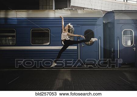 Stock Image - Caucasian woman dancing near train. Fotosearch