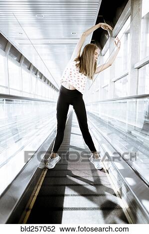 Stock Image - Caucasian woman dancing on moving walkway. Fotosearch