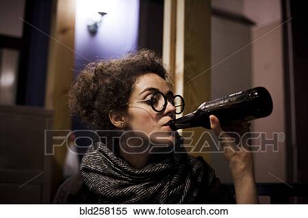 Stock Photography - Caucasian woman drinking bottle of beer. Fotosearch