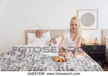 Stock Photograph - Caucasian woman eating breakfast in bed. Fotosearch
