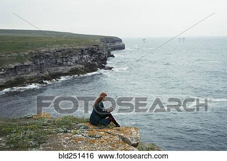Caucasian woman examining camera near ocean View Large Photo Image Stock Photograph - Caucasian woman examining camera near ocean. Fotosearch