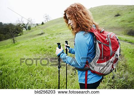 Stock Image - Caucasian woman hiking with walking sticks. Fotosearch