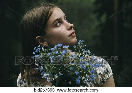 Stock Image - Caucasian woman holding flowers and looking up. Fotosearch