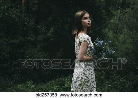 Caucasian woman holding flowers in forest View Large Photo Image Stock Photo - Caucasian woman holding flowers in forest. Fotosearch