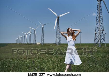 Stock Photo - Caucasian woman in field near wind turbines. Fotosearch