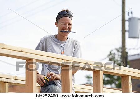 Stock Image - Caucasian woman laughing at construction site. Fotosearch