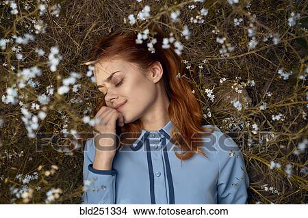 Picture - Caucasian woman laying in field of wildflowers. Fotosearch
