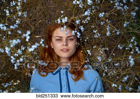 Stock Image - Caucasian woman laying in field of wildflowers. Fotosearch