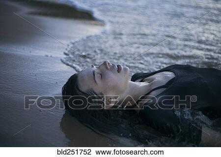 Caucasian woman laying on beach in waves View Large Photo Image Stock Image - Caucasian woman laying on beach in waves. Fotosearch