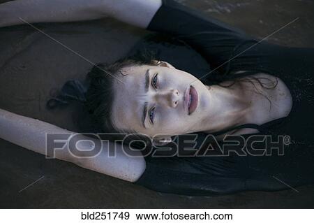 Stock Photo - Caucasian woman laying on beach in waves. Fotosearch