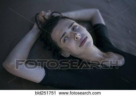 Stock Image - Caucasian woman laying on beach. Fotosearch