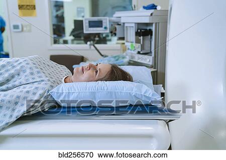 Stock Image - Caucasian woman laying on scanner table. Fotosearch