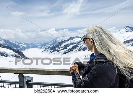 Caucasian woman leaning on railing admiring scenic view of mountains View Large Photo Image Picture - Caucasian woman leaning on railing admiring scenic view of mountains. Fotosearch