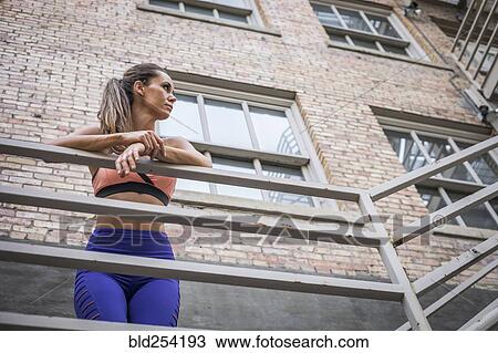 Stock Image - Caucasian woman leaning on urban railing. Fotosearch