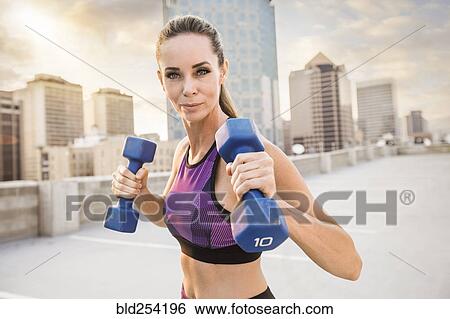 Caucasian woman lifting dumbbells on urban rooftop View Large Photo Image Stock Photograph - Caucasian woman lifting dumbbells on urban rooftop. Fotosearch