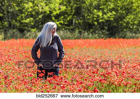 Stock Photo - Caucasian woman looking away in field of flowers. Fotosearch