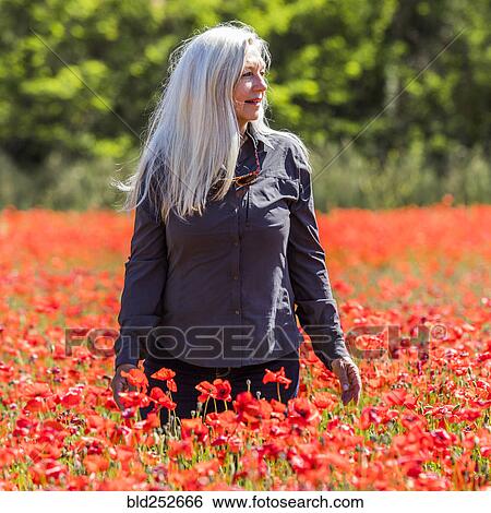 Stock Photograph - Caucasian woman looking away in field of flowers. Fotosearch