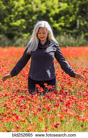 Stock Photography - Caucasian woman looking down at field of flowers. Fotosearch