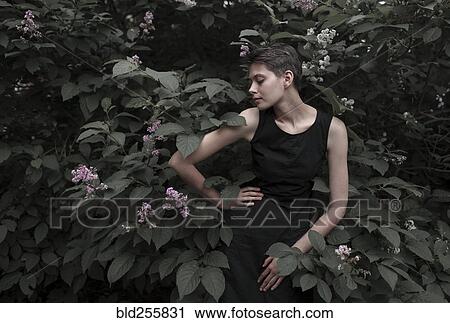 Stock Image - Caucasian woman near flowering tree with hand on hip. Fotosearch