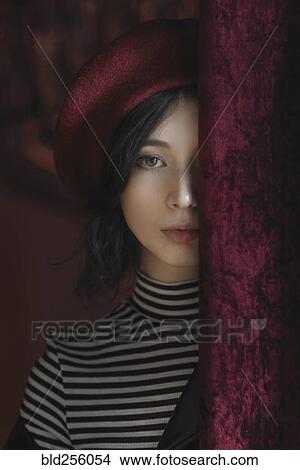 Picture - Caucasian woman peeking from behind curtain. Fotosearch