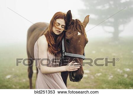 Stock Image - Caucasian woman petting horse. Fotosearch