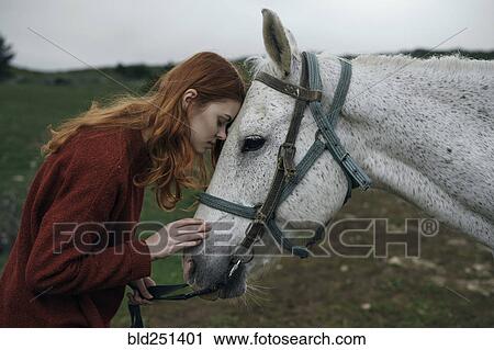 Stock Image - Caucasian woman petting horse. Fotosearch