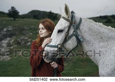 Stock Image - Caucasian woman petting horse. Fotosearch