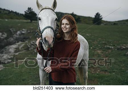 Stock Image - Caucasian woman petting horse. Fotosearch