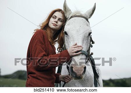 Stock Image - Caucasian woman petting horse. Fotosearch