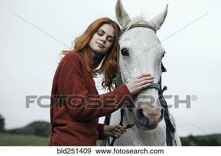 Stock Photo - Caucasian woman petting horse. Fotosearch