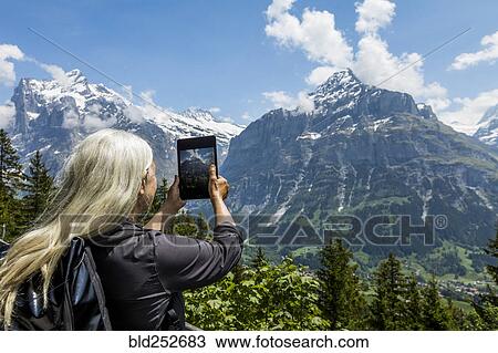Caucasian woman photographing mountain with digital tablet View Large Photo Image Stock Image - Caucasian woman photographing mountain with digital tablet. Fotosearch