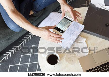 Stock Photograph - Caucasian woman photographing paperwork with cell phone. Fotosearch