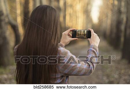Caucasian woman photographing path with cell phone View Large Photo Image Stock Photography - Caucasian woman photographing path with cell phone. Fotosearch