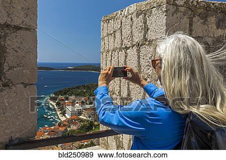 Caucasian woman photographing scenic view of ocean View Large Photo Image Stock Photo - Caucasian woman photographing scenic view of ocean. Fotosearch