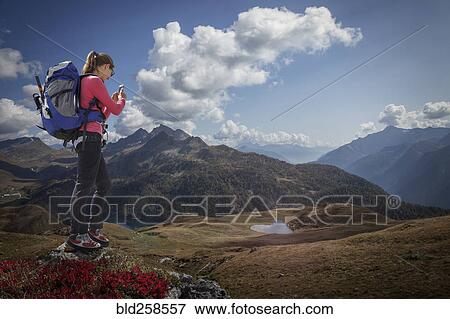 Caucasian woman photographing scenic view of landscape with cell phone View Large Photo Image Stock Photo - Caucasian woman photographing scenic view of landscape with cell phone. Fotosearch