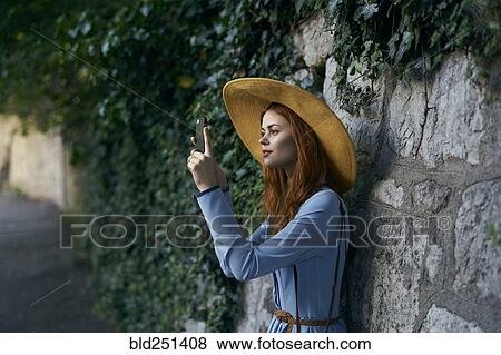 Caucasian woman photographing with cell phone near stone wall View Large Photo Image Stock Photo - Caucasian woman photographing with cell phone near stone wall. Fotosearch