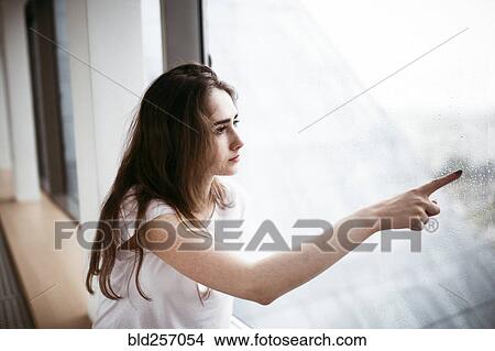 Caucasian woman pointing at rain on window View Large Photo Image Picture - Caucasian woman pointing at rain on window. Fotosearch