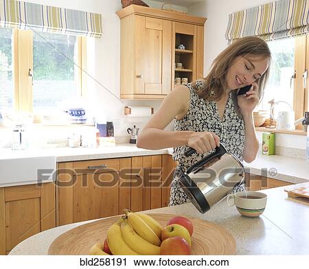 Caucasian woman poring coffee and talking on cell phone View Large Photo Image Stock Image - Caucasian woman poring coffee and talking on cell phone. Fotosearch