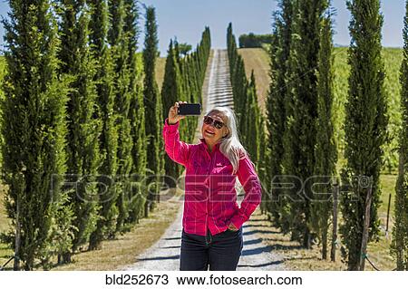 Caucasian woman posing for cell phone selfie on dirt road View Large Photo Image Stock Image - Caucasian woman posing for cell phone selfie on dirt road. Fotosearch