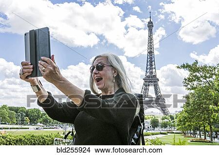 Caucasian woman posing for digital tablet selfie near Eiffel Tower View Large Photo Image Picture - Caucasian woman posing for digital tablet selfie near Eiffel Tower. Fotosearch
