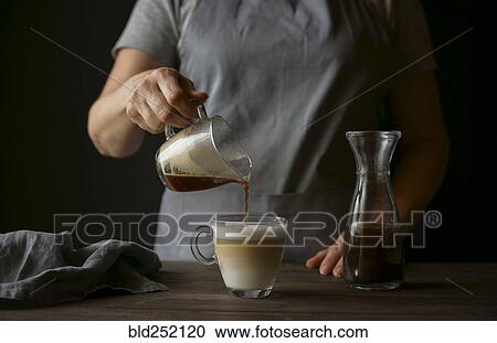 Stock Image - Caucasian woman pouring coffee into latte. Fotosearch