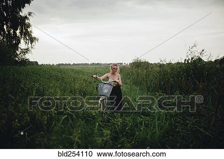 Caucasian woman pushing a bicycle in field View Large Photo Image Stock Image - Caucasian woman pushing a bicycle in field. Fotosearch