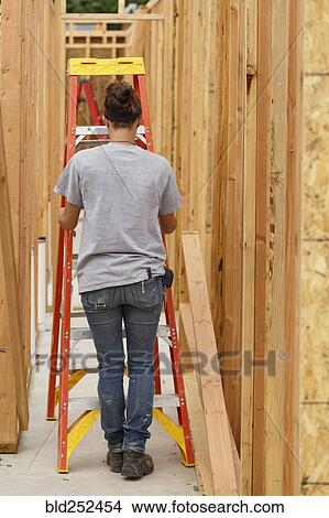 Picture - Caucasian woman pushing ladder at construction site. Fotosearch